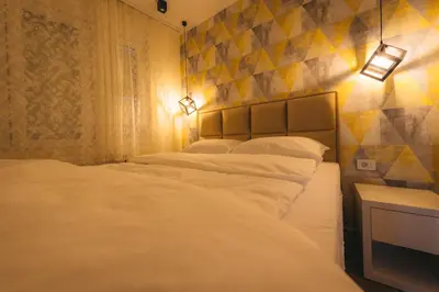 two beds in a room with lights on the wall at Apartman Dias in Niš