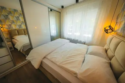 a bedroom with a large white bed and a mirror at Apartman Dias in Niš