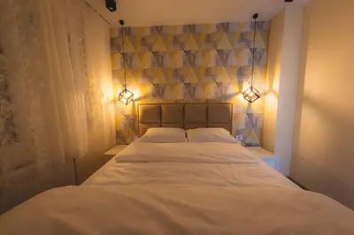 a bedroom with a bed with two pillows and lights at Apartman Dias in Niš