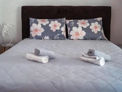 a bed with two pillows and three towels on it at Apartman Ristić in Vranje