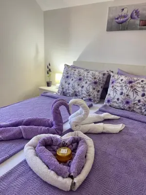 a purple bed with two swans made to look like hearts at Lily Cozy Apartment in Niš