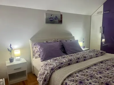 a bedroom with a large bed with purple pillows at Lily Cozy Apartment in Niš