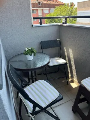 a table and two chairs on a balcony with a table and a plant at Lily Cozy Apartment in Niš