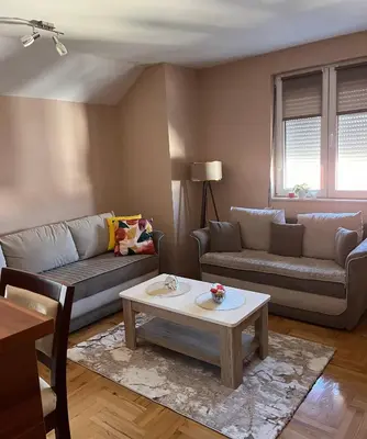 a living room with two couches and a coffee table at Lily Cozy Apartment in Niš
