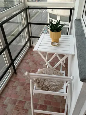 a cat sleeping on a chair under a table on a balcony at Loli apartman 2 in Kraljevo