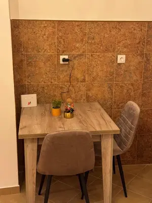a wooden table with two chairs in a room at Loli apartman 2 in Kraljevo