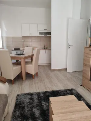 a living room with a table and chairs and a kitchen at Apartman Sofija in Vrnjačka Banja