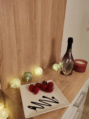 a table with a plate of strawberries and a bottle of wine at Apartman Sofija in Vrnjačka Banja