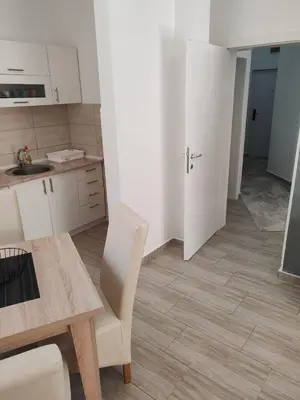 a kitchen with white cabinets and a table and chair at Apartman Sofija in Vrnjačka Banja