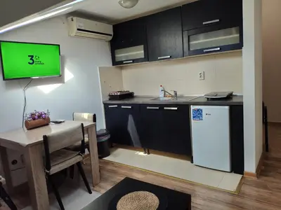 a kitchen with a table and a tv on the wall at DeFakto in Vrnjačka Banja