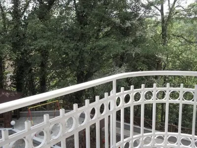 a white metal fence with trees in the background at Apartman Sanja in Vrnjačka Banja
