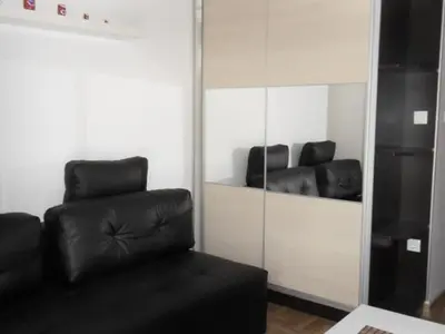 a living room with a black leather couch and a mirror at Apartman Sanja in Vrnjačka Banja