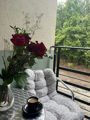 a table with a vase of roses and a cup of coffee at Apartman Sanja 2 in Vrnjačka Banja
