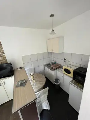 a small kitchen with white cabinets and a table at Apartman Sanja 2 in Vrnjačka Banja