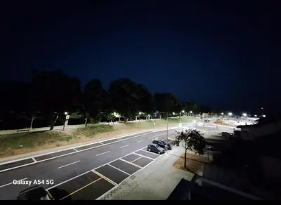 a parking lot at night with cars parked on the street at Apartman Centrala in Pirot