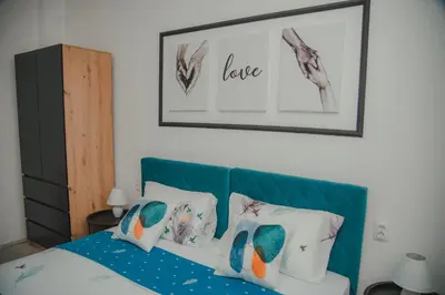 a bedroom with a bed with a blue headboard and pillows at Jes Apartments in Leskovac