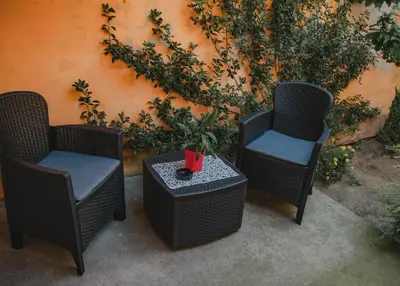 three wicker chairs and a table in front of a wall at Jes Apartments in Leskovac
