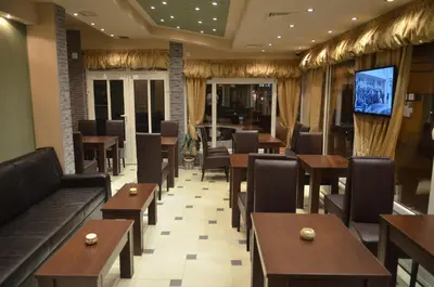 a restaurant with tables and chairs and a tv at Garni Hotel Lion in Jagodina