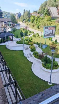 a park with curved paths and bushes and a sign at Apartman 22, Brzeće Centar in Mramor