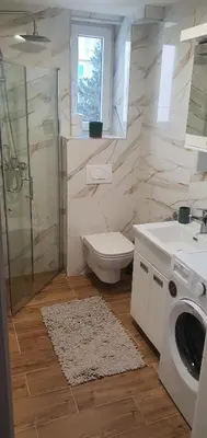 a bathroom with a toilet and a sink and a washing machine at Apartman TADEJ & FREE PARKING in Vrnjci