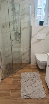 a bathroom with a shower and a toilet and a rug at Apartman TADEJ & FREE PARKING in Vrnjci