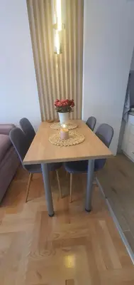 a wooden table with chairs and a vase of flowers on it at Apartman TADEJ & FREE PARKING in Vrnjci