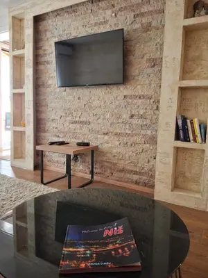 a living room with a tv on a brick wall at A&S Apartments Nis in Niš