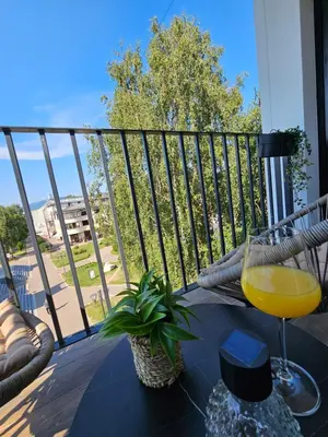 a glass of orange juice sitting on a table on a balcony at Apartman KING CENTAR in Vrnjačka Banja