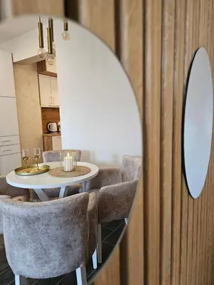 a dining room with a table and chairs and a mirror at Apartman KING CENTAR in Vrnjačka Banja