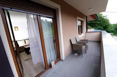 a balcony with sliding glass doors and a table and chair at Apartmani Smiljković90 in Aleksandrovac