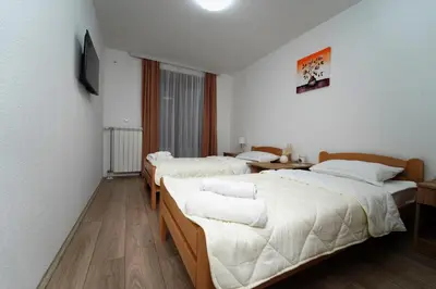 two beds in a room with white walls and wooden floors at Apartmani Smiljković90 in Aleksandrovac