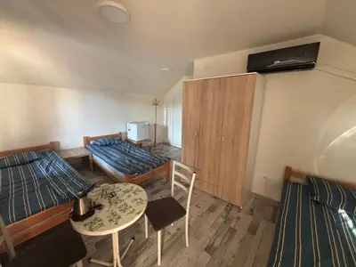 a room with two beds and a table and chairs at Apartmani Andjeo in Kraljevo