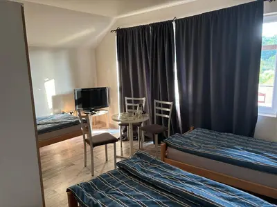 a room with two beds and a table and chairs at Apartmani Andjeo in Kraljevo