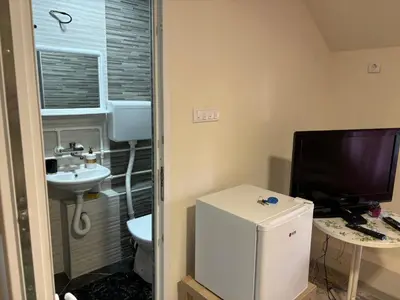 a small bathroom with a toilet and a television at Apartmani Andjeo in Kraljevo