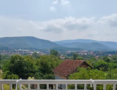 a house with a white fence and mountains in the background at Apartman sa pogledom na Ozren in Soko Banja