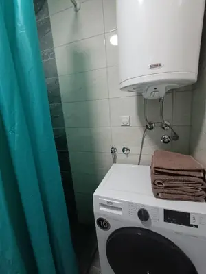 a washing machine in a bathroom with a blue shower curtain at Luksuzni Apartman Ema in Pirot