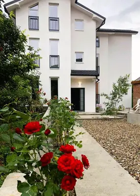 a white building with red flowers in front of it at Vas Dom in Soko Banja