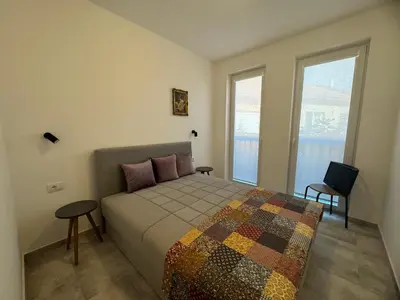 a bedroom with a bed with two tables and two windows at Vas Dom in Soko Banja
