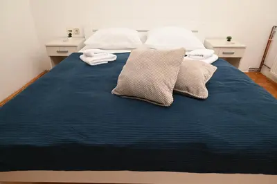 a bed with blue sheets and two pillows on it at Apartmani Timacum in Knjazevac.