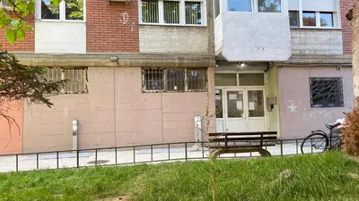a bench sitting in the grass in front of a building at Stan na Dan - Centar - Besplatan parking in Niš