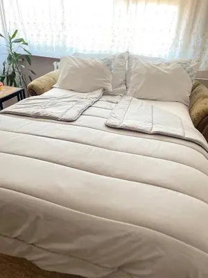 a bed with white sheets and pillows on it at Stan na Dan - Centar - Besplatan parking in Niš