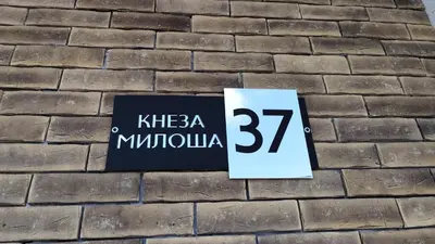 a sign on the side of a brick wall at Apartman Đorđe in Vrnjačka Banja