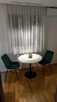 a white table and two green chairs in front of a window at Apartman Đorđe in Vrnjačka Banja