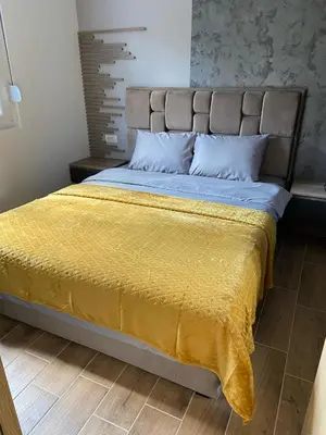 a bedroom with a bed with a yellow blanket on it at SOUL Apartman in Soko Banja