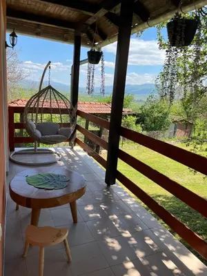 a porch with a swing and a table and a chair at Vikendica Bellini 3 in Soko Banja