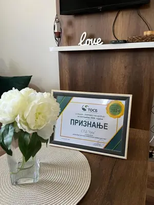 a vase with white flowers and a sign on a table at Vikendica Bellini 3 in Soko Banja