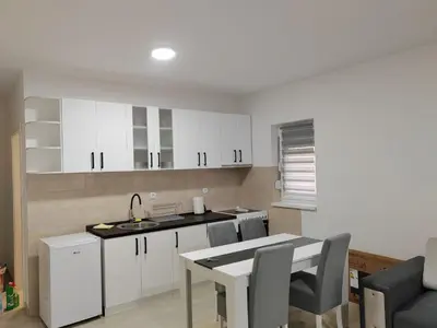 a kitchen with white cabinets and a table and a sink at Apartman Petrovic 3 in Soko Banja