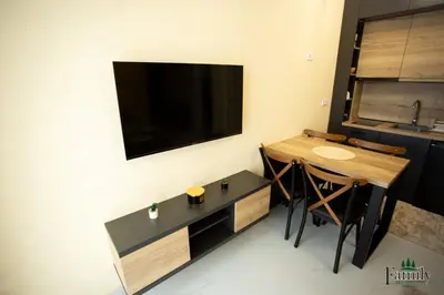 a small kitchen with a table and a tv on the wall at FAMILY APARTMENTs 3 in Vrnjačka Banja