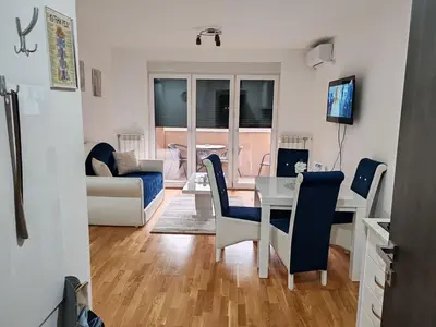 a living room with a table and blue chairs at Apartmani Lucky Place in Vrnjačka Banja