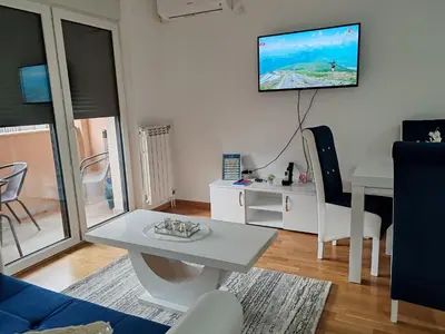 a living room with a table and a tv on the wall at Apartmani Lucky Place in Vrnjačka Banja